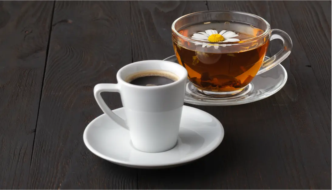 A cup of coffee (espresso) and a cup of tea on a dark table